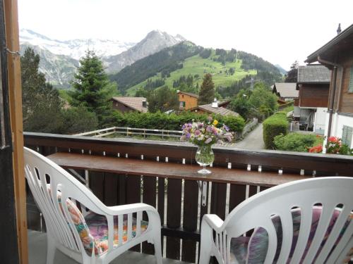 a balcony with two chairs and a vase of flowers at Apartment Sunnegruess by Interhome in Adelboden