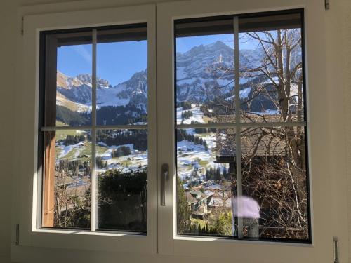 a window with a view of a snowy mountain at Apartment Sunnegruess by Interhome in Adelboden