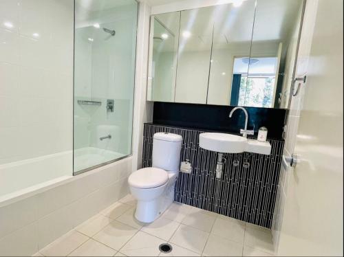 a bathroom with a toilet and a sink and a shower at Cozy Zetland 2 bedroom apt with pool, gym and parking in Sydney
