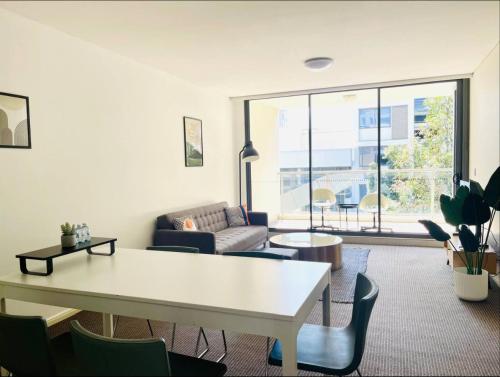 a living room with a white table and chairs at Cozy Zetland 2 bedroom apt with pool, gym and parking in Sydney