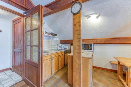 a kitchen with a wooden door and a clock on the wall at Magnimon 2 - Le Charme Rustique in Villard-Reculas