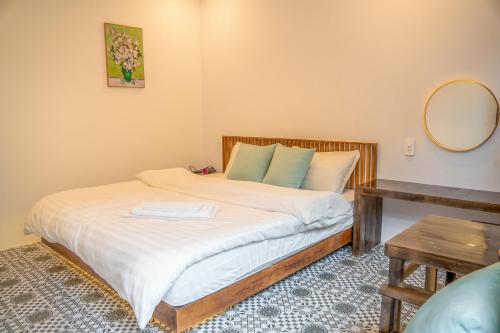 a bedroom with a bed with a mirror and a table at MoCha House in Làng Môn