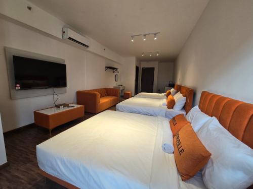 a hotel room with two beds and a flat screen tv at K Avenue Kota Kinabalu by Merveille - Sabah in Donggongon