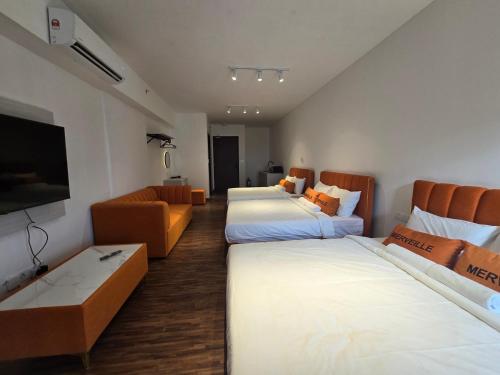 a hotel room with two beds and a couch at K Avenue Kota Kinabalu by Merveille - Sabah in Donggongon