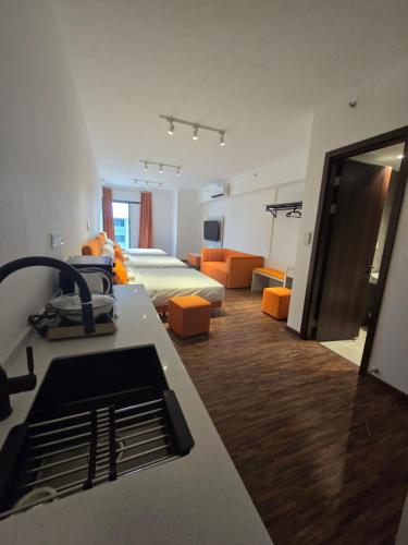 a room with two beds and a kitchen with orange chairs at K Avenue Kota Kinabalu by Merveille - Sabah in Donggongon