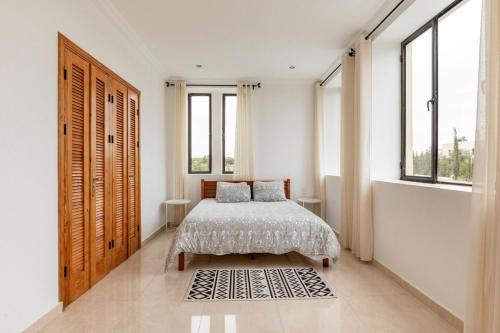 a bedroom with a bed and windows and a rug at Villa Louda in Essaouira