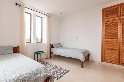 a bedroom with two beds and a bench and a window at Villa Louda in Essaouira