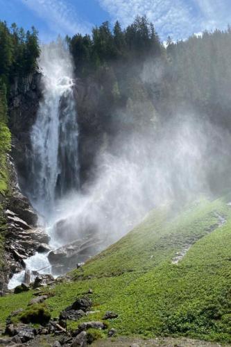 a waterfall on the side of a hill with a field at Apartment Chalet Bijou- 1 OG by Interhome in Lenk