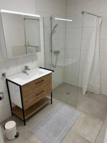 a bathroom with a sink and a shower with a mirror at Gästeapartment - Kirchweg 4 in Rainau in Rainau