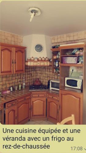 - une cuisine avec des placards en bois et un four micro-ondes dans l'établissement Chambre Double dans une maison, à Bourges