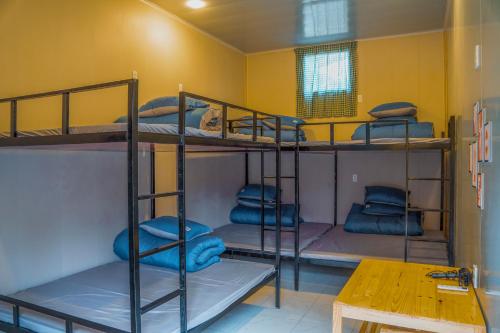 a room with three bunk beds and a table at MoCha House in Làng Môn