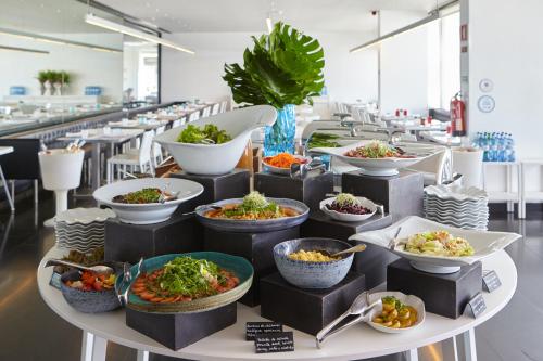 a buffet with bowls of food on a table at Altis Belem Hotel & Spa, a Member of Design Hotels in Lisbon