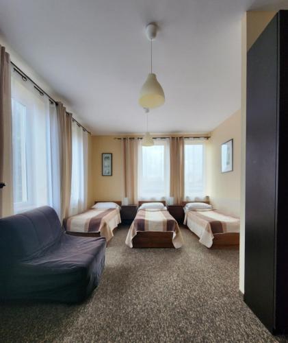 a hotel room with two beds and a couch at Hostel Zamość - pokoje gościnne - bezpłatny parking in Zamość