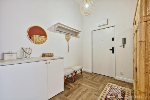 a kitchen with white cabinets and a mirror on the wall at Kolorova Apart by LookAp - darmowy parking w centrum Łodzi! in Łódź