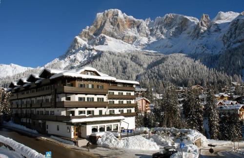 a building in front of a mountain with snow at Hotel Colfosco in San Martino di Castrozza