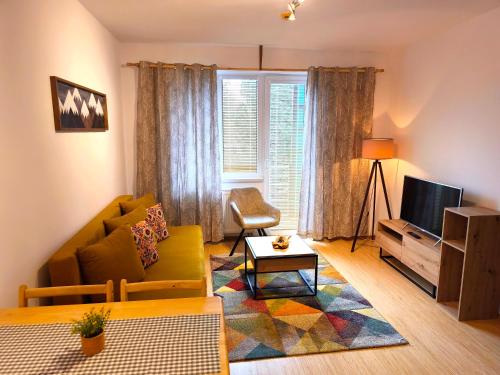 a living room with a couch and a tv at Apartments Tatra Olla - Tatranská Lomnica in Tatranská Lomnica