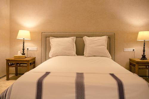 a bedroom with a bed with two lamps and two tables at Atlas Retreat Luxury Bed and Breakfast in Beni Mellal