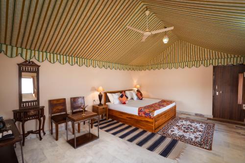 a bedroom with a bed and a chair and a table at Desert Vista Camp Jaisalmer in Jaisalmer