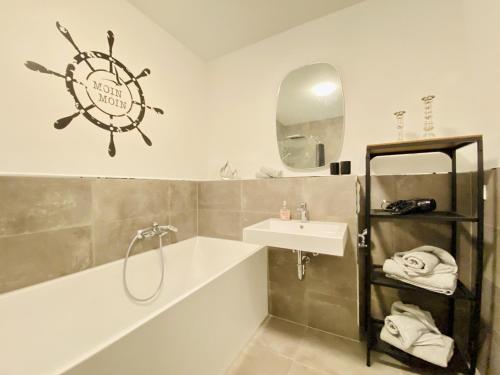 a bathroom with a sink and a bath tub and a clock at Ferienwohnung Windflüchter Parkvillen Carlota und Candela Baabe in Baabe