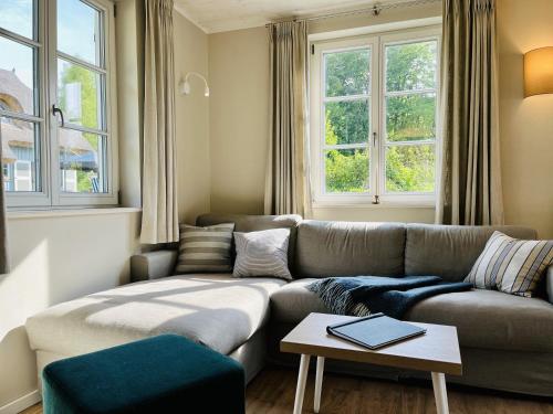 Una sala de estar con un sofá y dos ventanas. en Ferienhaus Mee h r Zeit 07 Feriendorf Klein Stresow Rügen by ruyastay, en Putbus