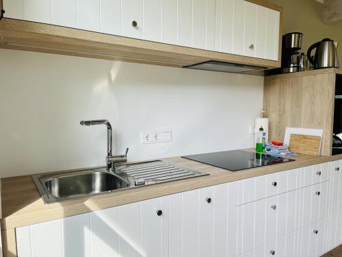 Ferienhaus Strandflieder 05 Feriendorf Klein Stresow Rügen by ruyastay في بوتبوس: مطبخ مع حوض ودواليب بيضاء