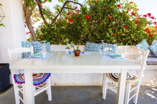 a white table and chairs with red flowers at Harama Hotel Schinousa in Skhoinoussa