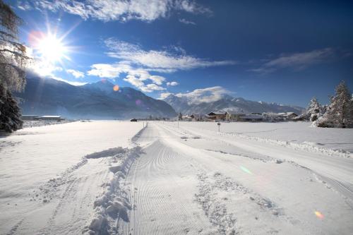 a snow covered road with the sun in the background at Gästehaus Trixl in Zell am See