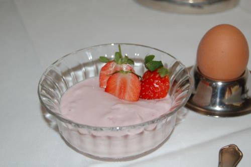 a bowl of strawberries and an egg on a table at Hotel Deichvoigt in Cuxhaven