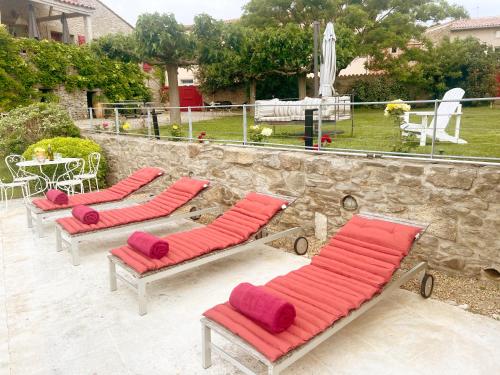 une rangée de chaises longues avec des coussins rouges sur une terrasse dans l'établissement Les Oliviers, à Cesseras