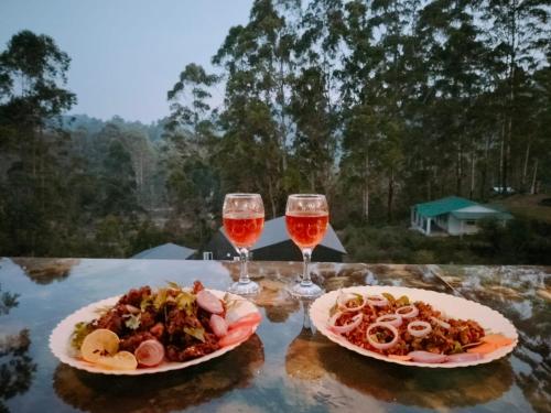 two plates of food and two glasses of wine on a table at IInfinity Kodaikanal in Kūkkāl