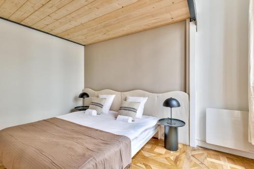 a bedroom with a white bed with a wooden ceiling at NOCNOC Le Trianon in Lyon