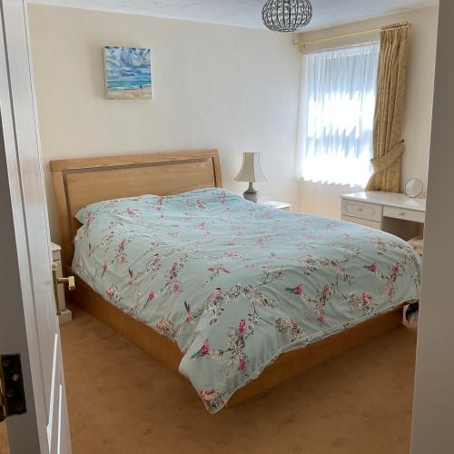 a bedroom with a bed with a floral bedspread at 2 Bed Ilfracombe Seafront Apartment with stunning views in Ilfracombe