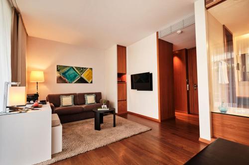 a living room with a couch and a tv at RIVA - Das Hotel am Bodensee in Konstanz