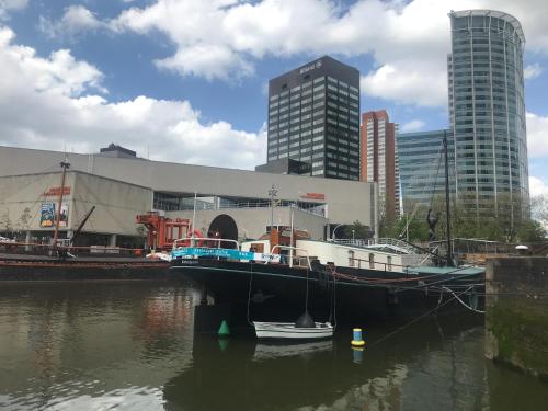 a boat docked in the water in front of a city at Boat Rooms on Water hele schip in Rotterdam