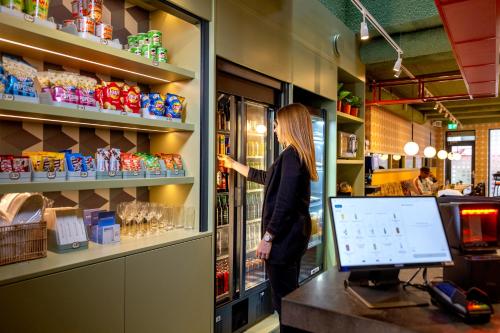 a woman standing in a grocery store buying food at Tourist Inn One Amsterdam in Amsterdam