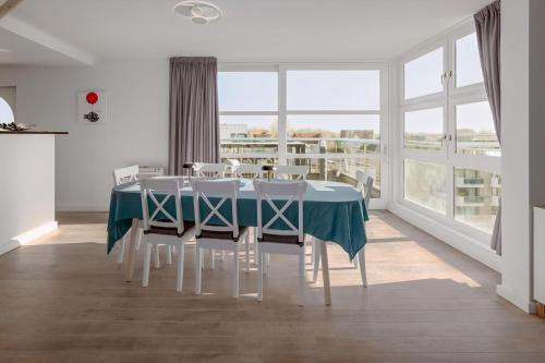 comedor con mesa azul y sillas blancas en Nausicaa 0501 G, en Oostduinkerke