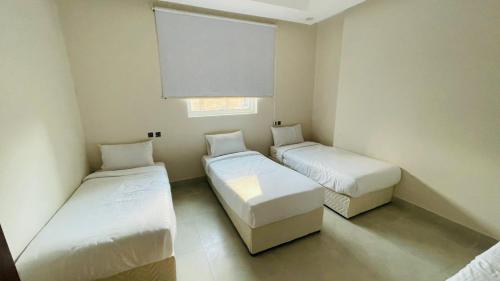 a small room with two beds and a window at فندق اوتادالمتحدة الذهبي الروضة 4 in Al Khansāk