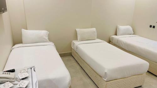 two beds in a small room with a phone and a phone at فندق اوتادالمتحدة الذهبي الروضة 4 in Al Khansāk