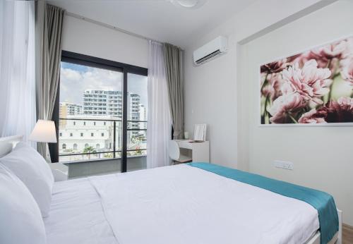 a bedroom with a white bed and a large window at Amelius Pool Apartments in Caesar Resort SPA, Long Beach in Perivolia tou Trikomou