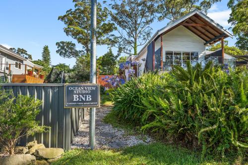 a sign in the grass in front of a house at Romanic Garden View 1 bed Apartment with ocean views at Stanwell Tops in Stanwell Park