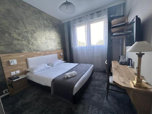 a bedroom with a bed and a desk and a television at Brit Hotel Privilège Le Royal - Centre Gare in Troyes