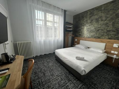 a bedroom with a bed and a desk and a window at Brit Hotel Privilège Le Royal - Centre Gare in Troyes