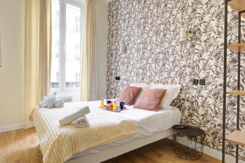 - une chambre avec un lit et un mur recouvert de papier peint dans l'établissement Bluestay 47 - Appartement au cœur de Paris, à Paris