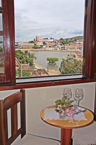 a table with two glasses and a window with a view at Pousada Solar Do Triunfo in Triunfo