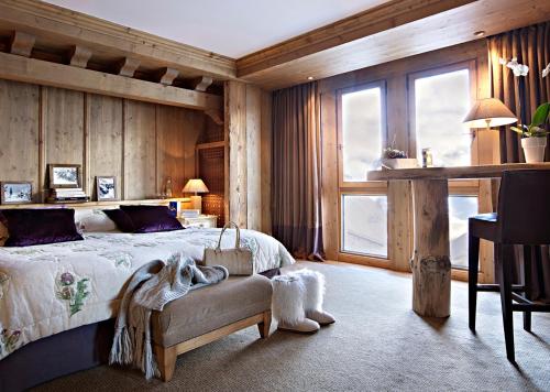 a bedroom with a bed and a chair and a window at Hôtel Les Barmes De l'Ours in Val-d'Isère