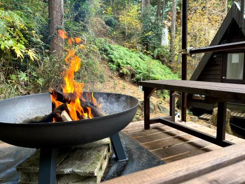 a fire pit with flames in it next to a picnic table at 南箱根ツリーハウス in Kannami