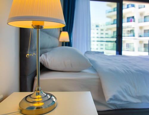 a lamp sitting on a table next to a bed at Neron Family Sea View Apartment in Caesar Resort & SPA, Long Beach in Perivolia tou Trikomou