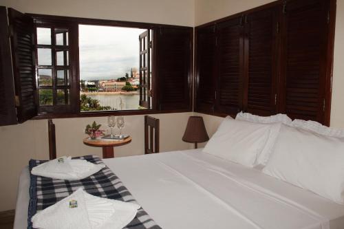 a bedroom with a white bed with a window at Pousada Solar Do Triunfo in Triunfo