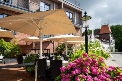 a patio with tables and umbrellas and flowers at Hotel Birke - Appartments Waldesruh in Kiel