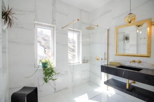 a white bathroom with a sink and a mirror at MareEterno in Ios Chora